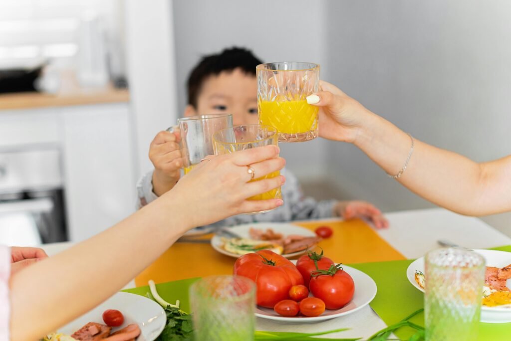 Happy family enjoying a healthy breakfast together, clinking glasses of orange juice.